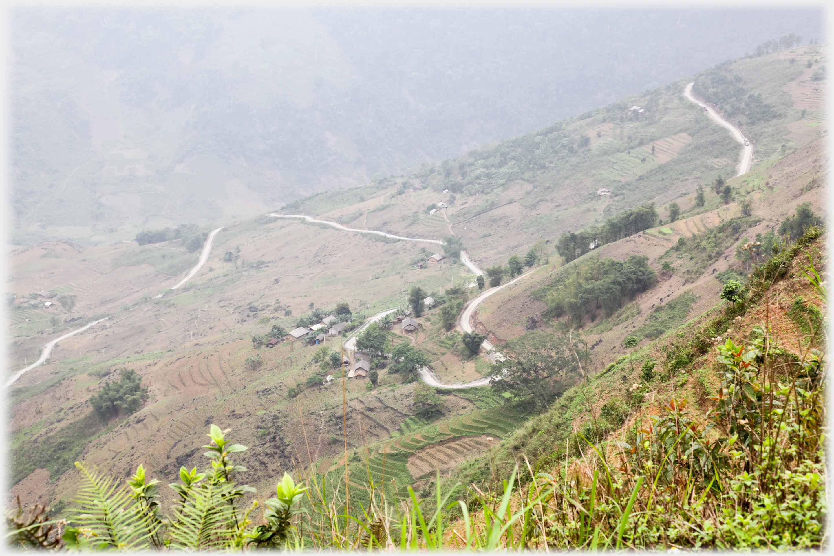 The view down a wide hillside with a road curving back and forth.