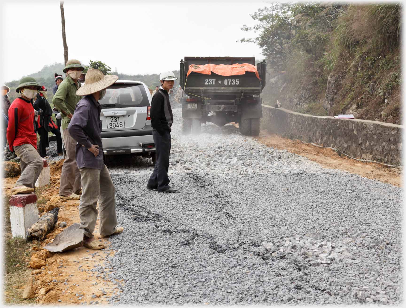 Workers standing beside newly laid road.