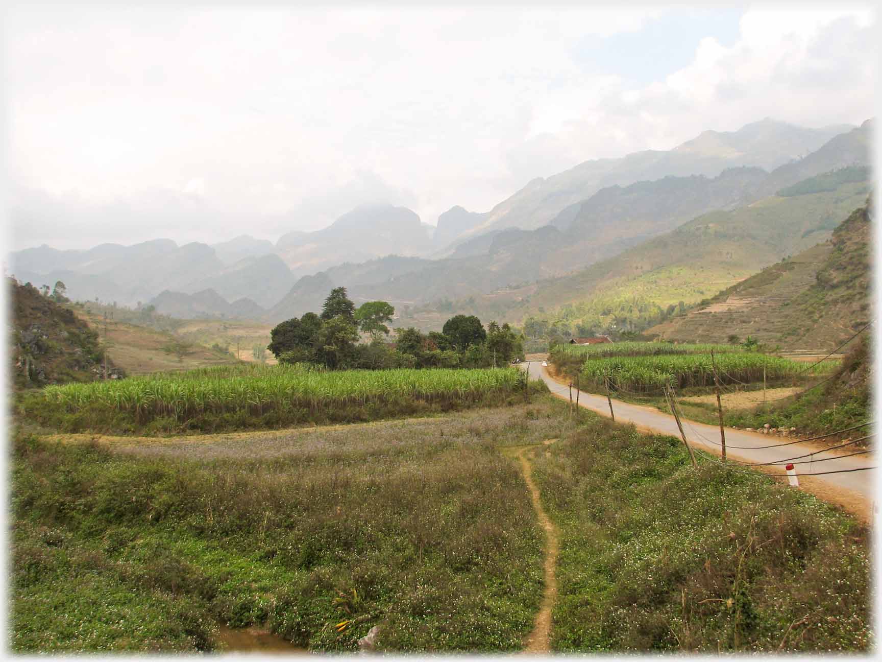Road running, in wide valley, towards hills.