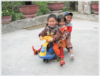 Three children on a child's scooter.