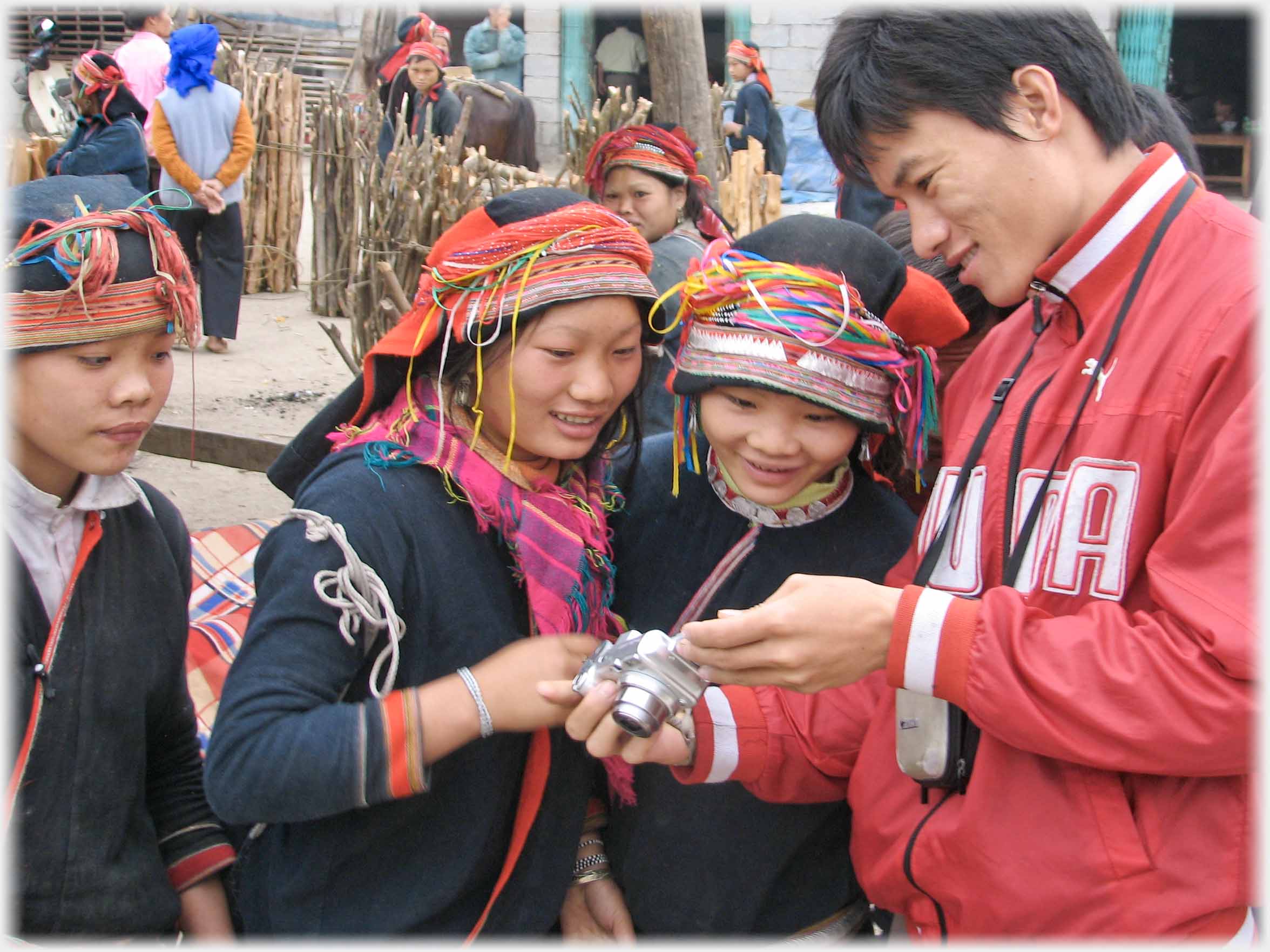 Man showing back of camera to two women.