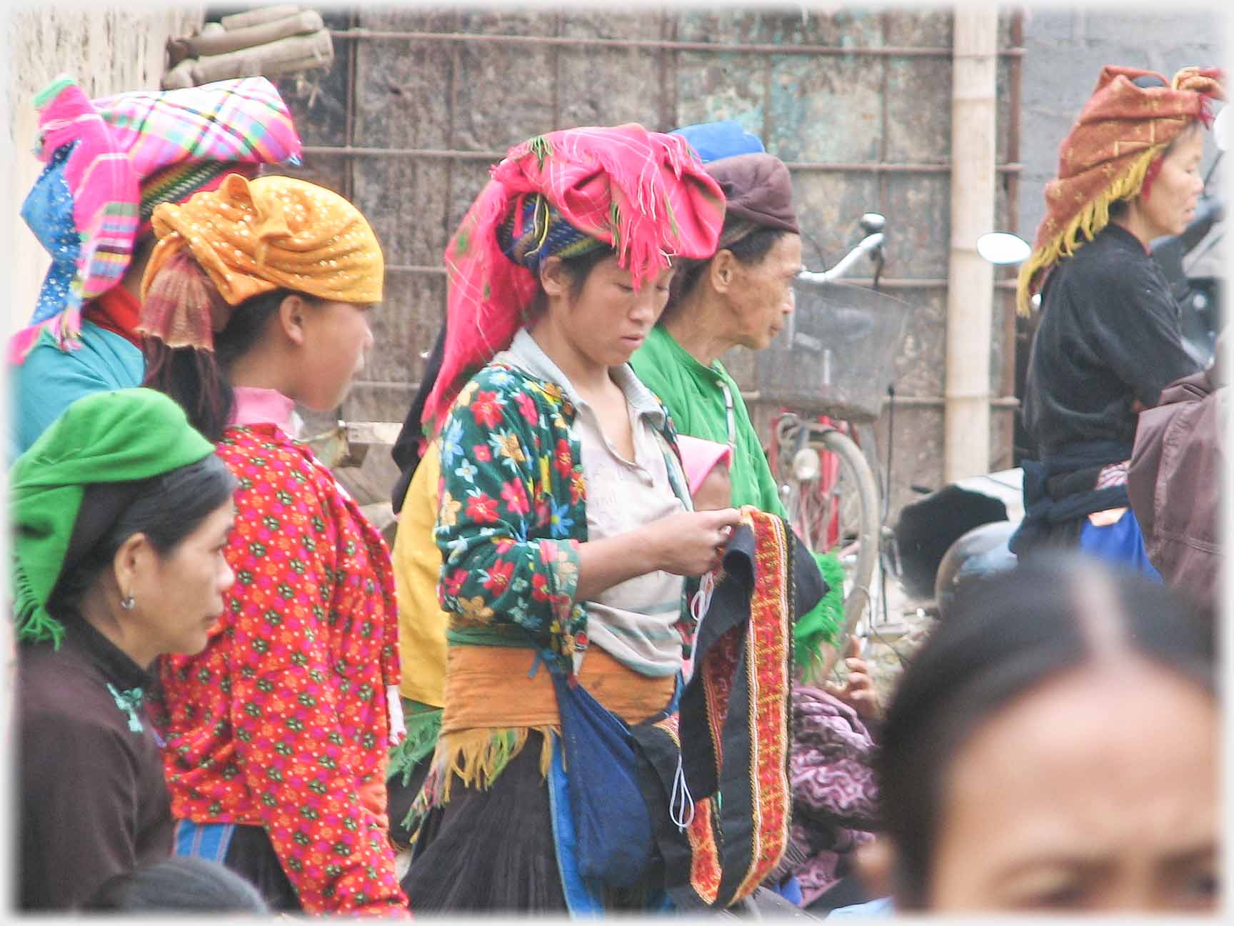 Woman with large head cloth examining fabric.