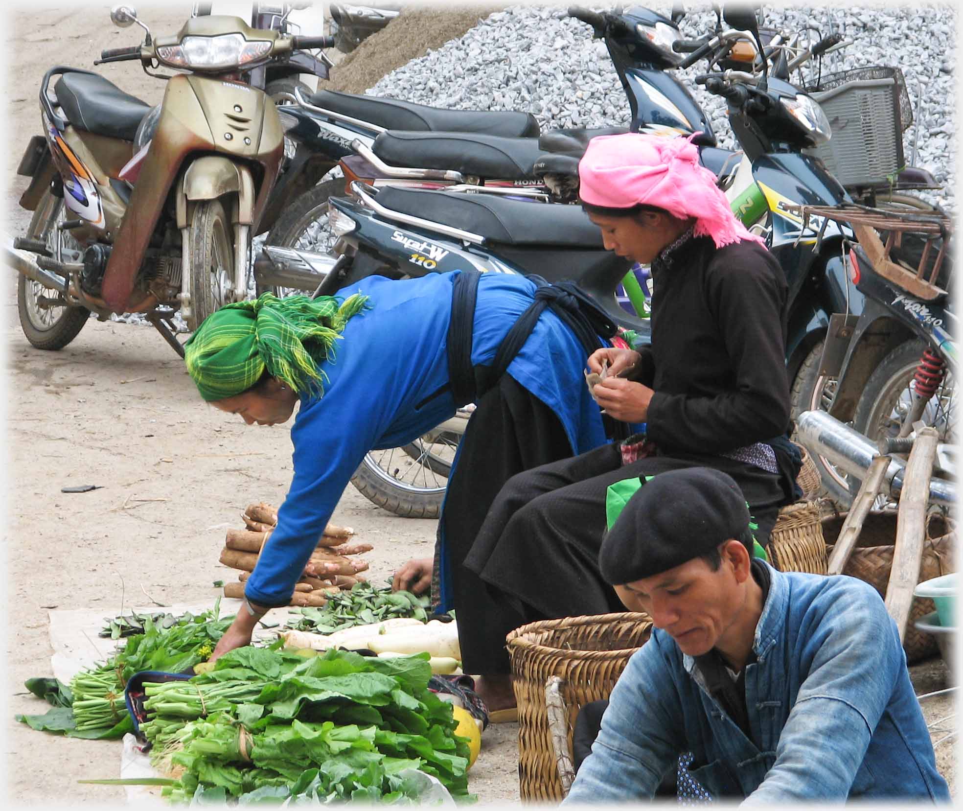 Woman in long blue overshirt arranging vegetables.