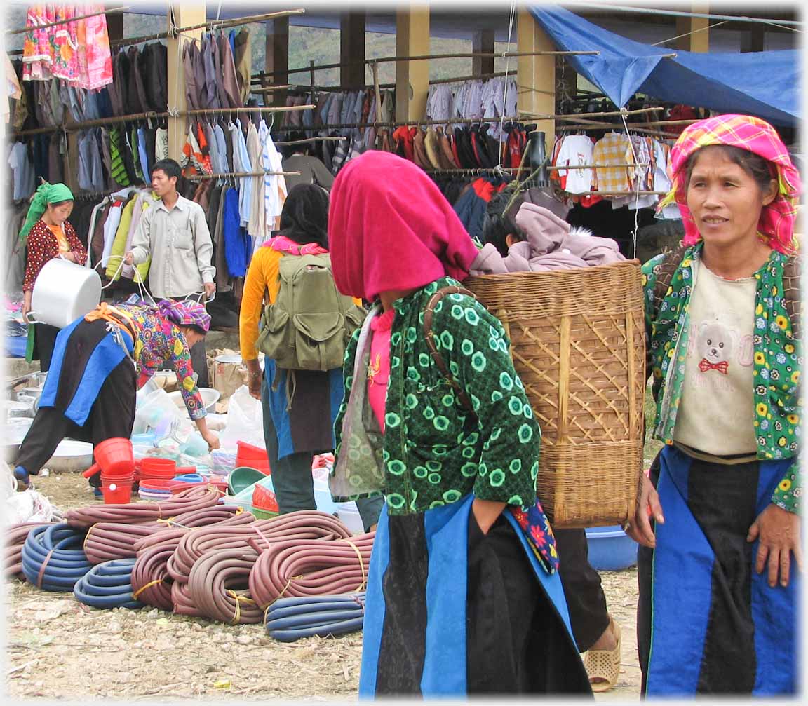 Woman with magenta headscarf, green jacket, and back-basket.
