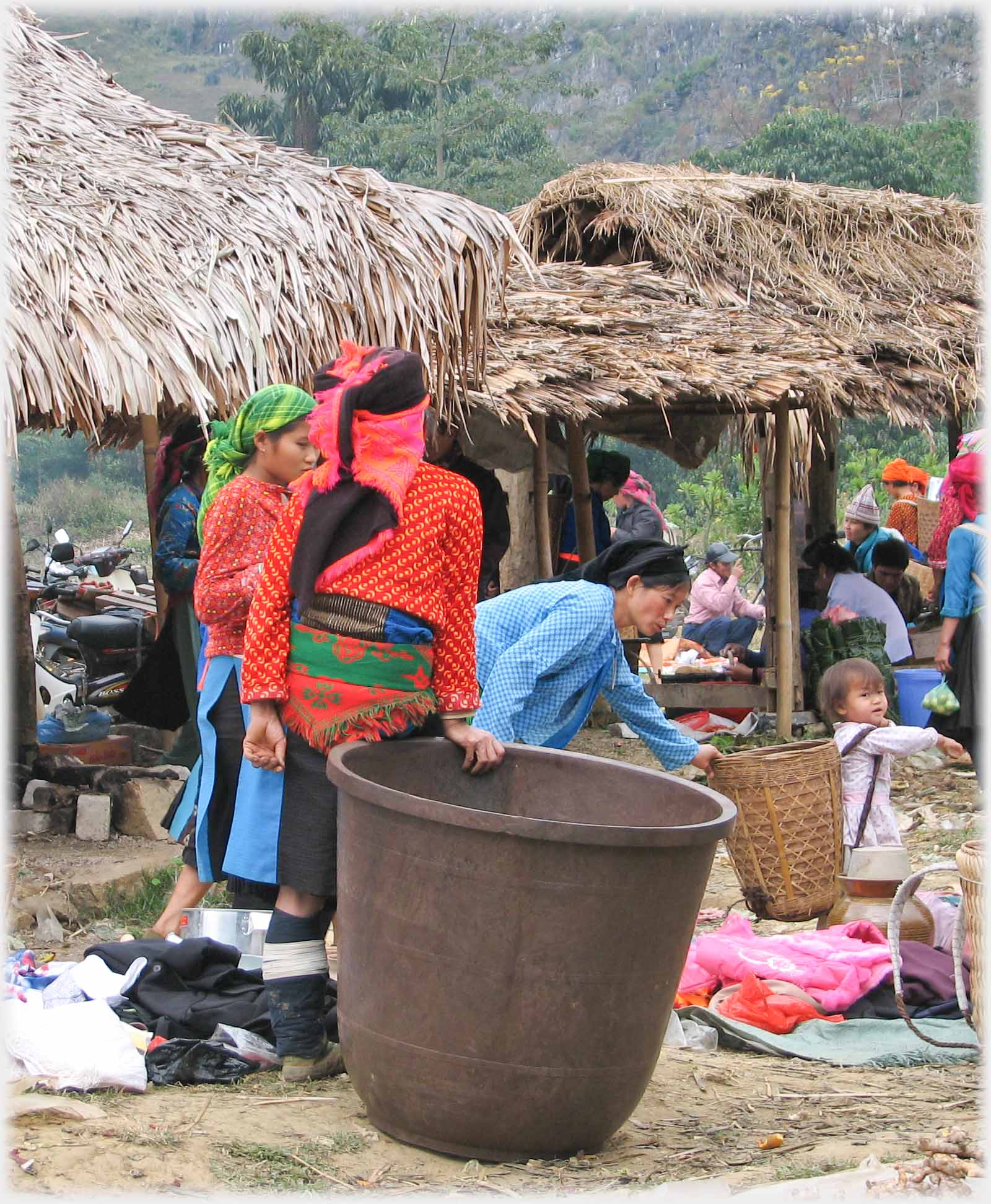 Back of woman in orange top leaning on large container.