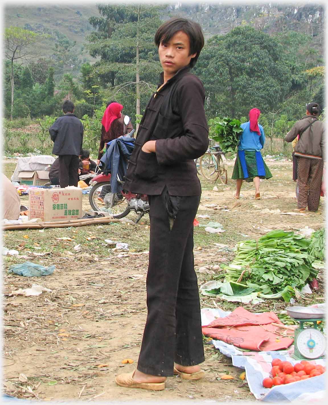 Man standing sidways on and looking over shoulder at camera, black jacket.