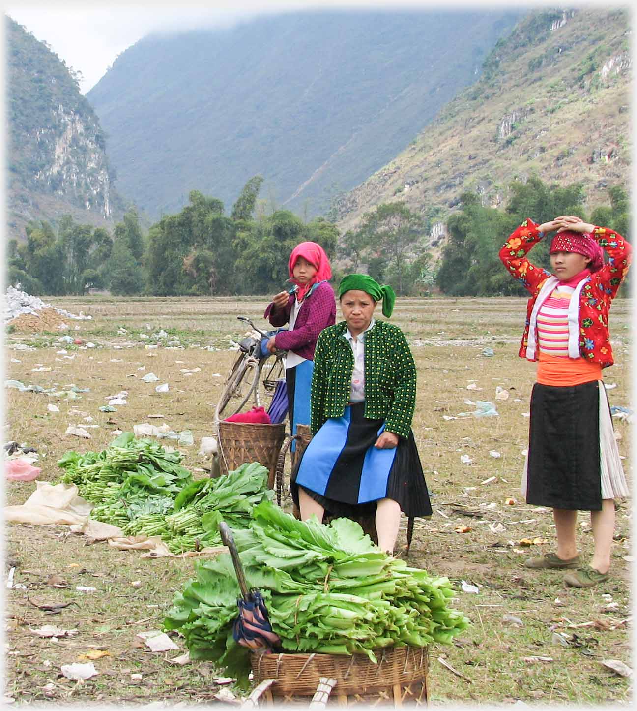 Three women and back-basket of green vegetables.
