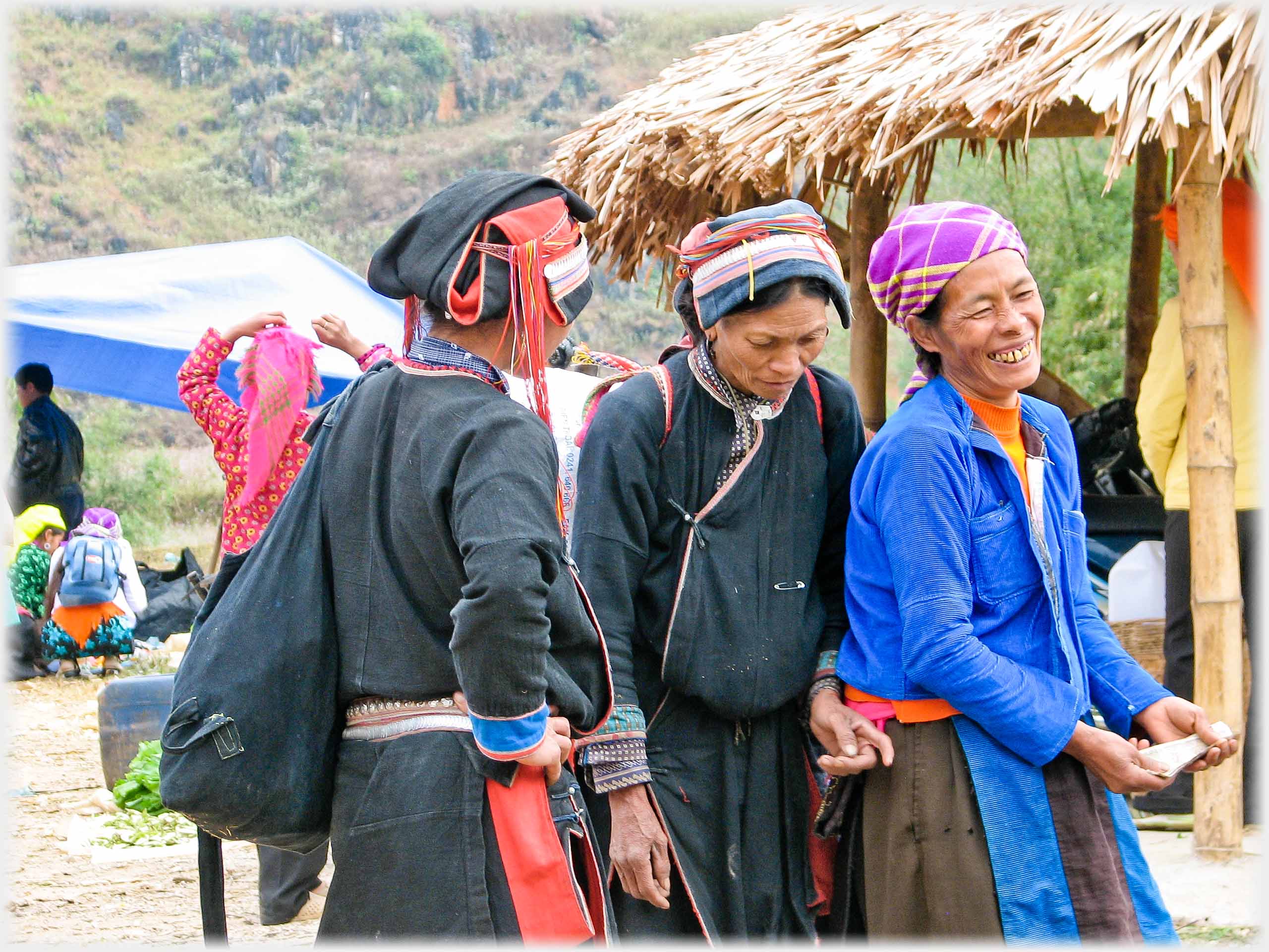 Three women laughing as one seems to be pretending to take money from another.