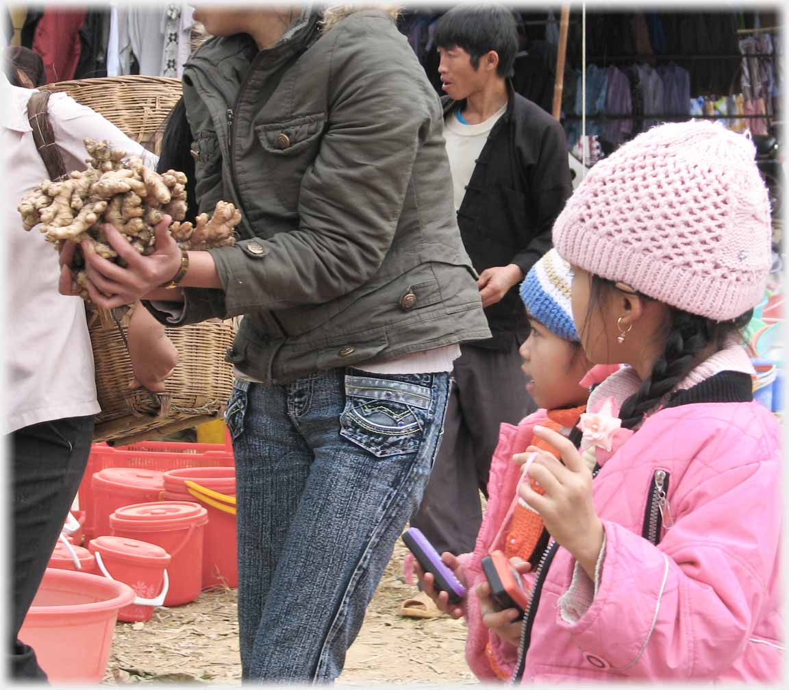 Woman clutching large handful of ginger watched by two girls.