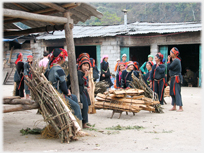 Women around yard with bundles of branches.