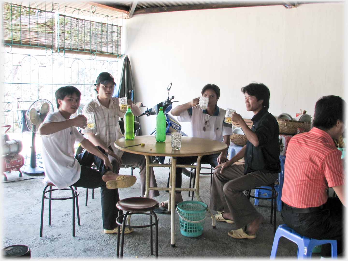 Four men around table raising beer glasses.