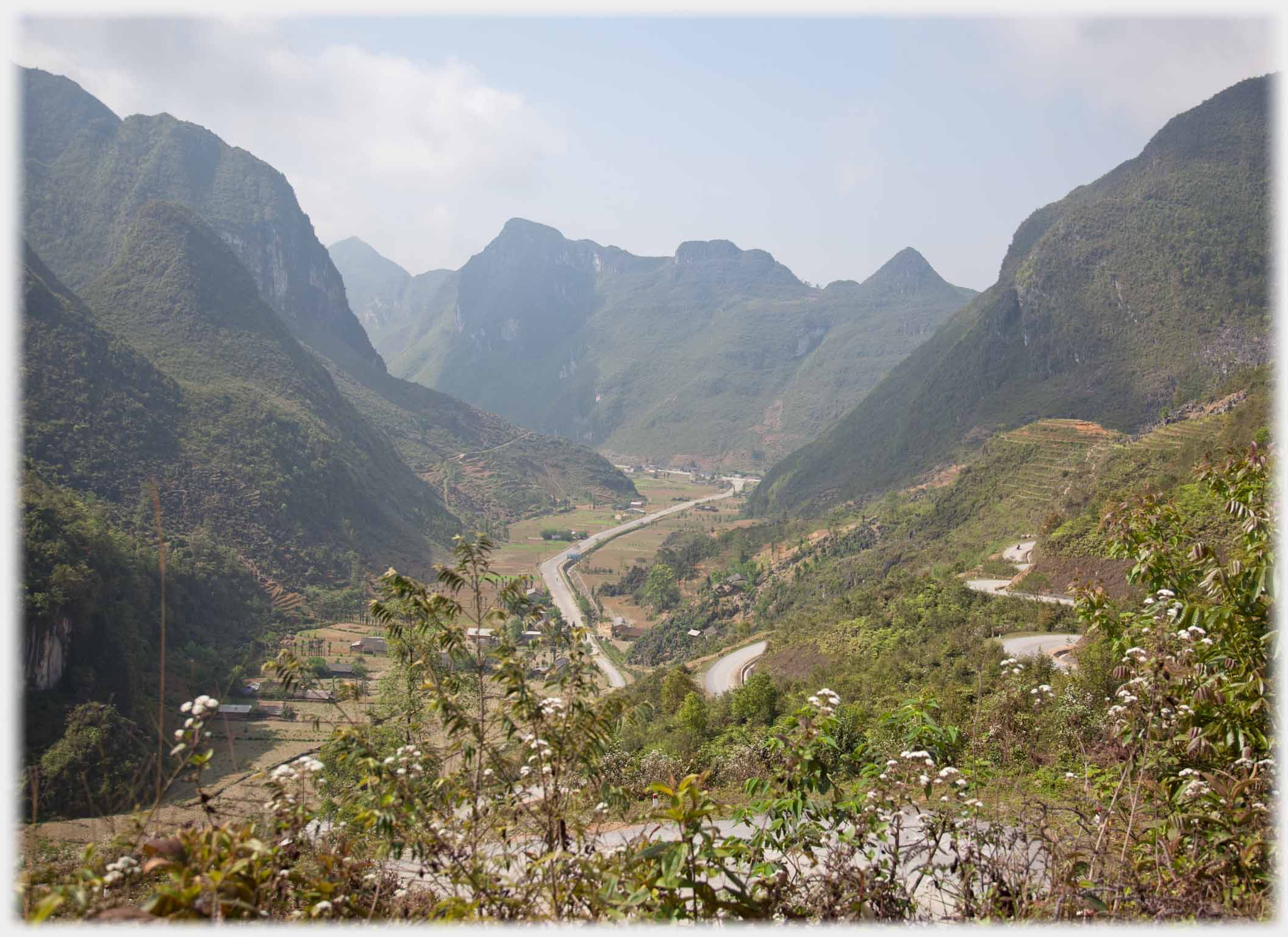 Looking down into deep valley, road curving in and out of view going down.