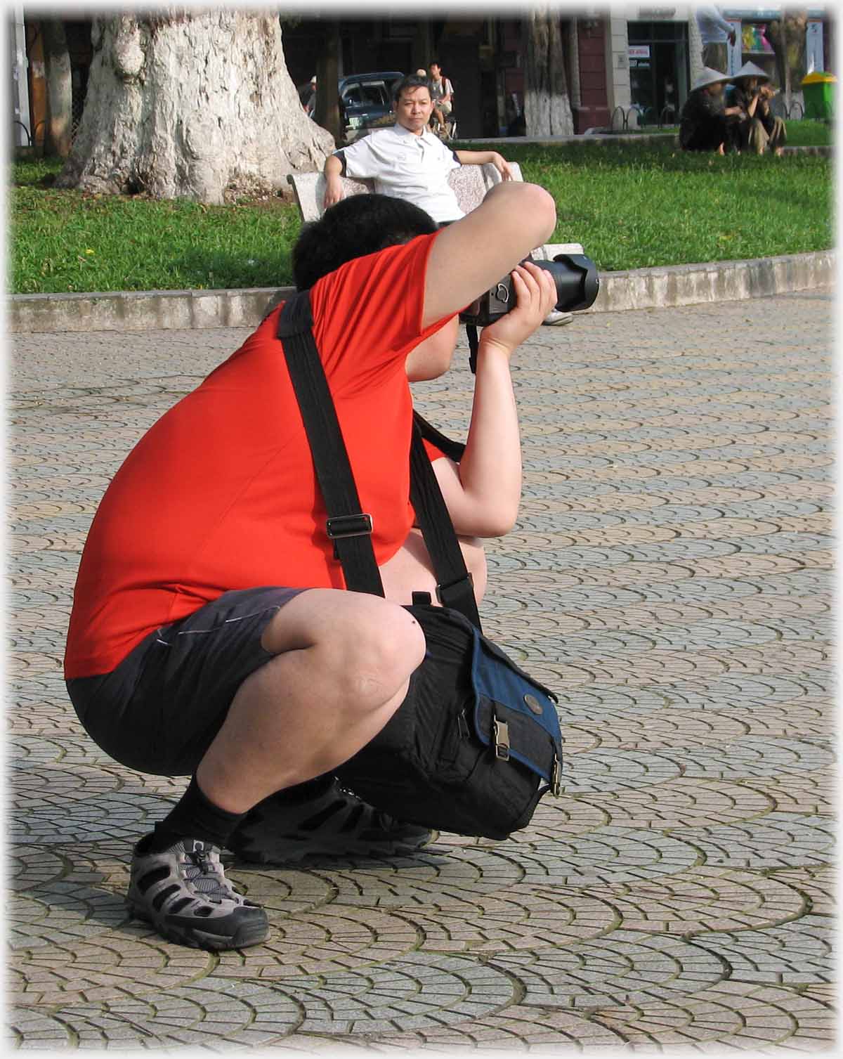Overweight photographer squatting taking shot.