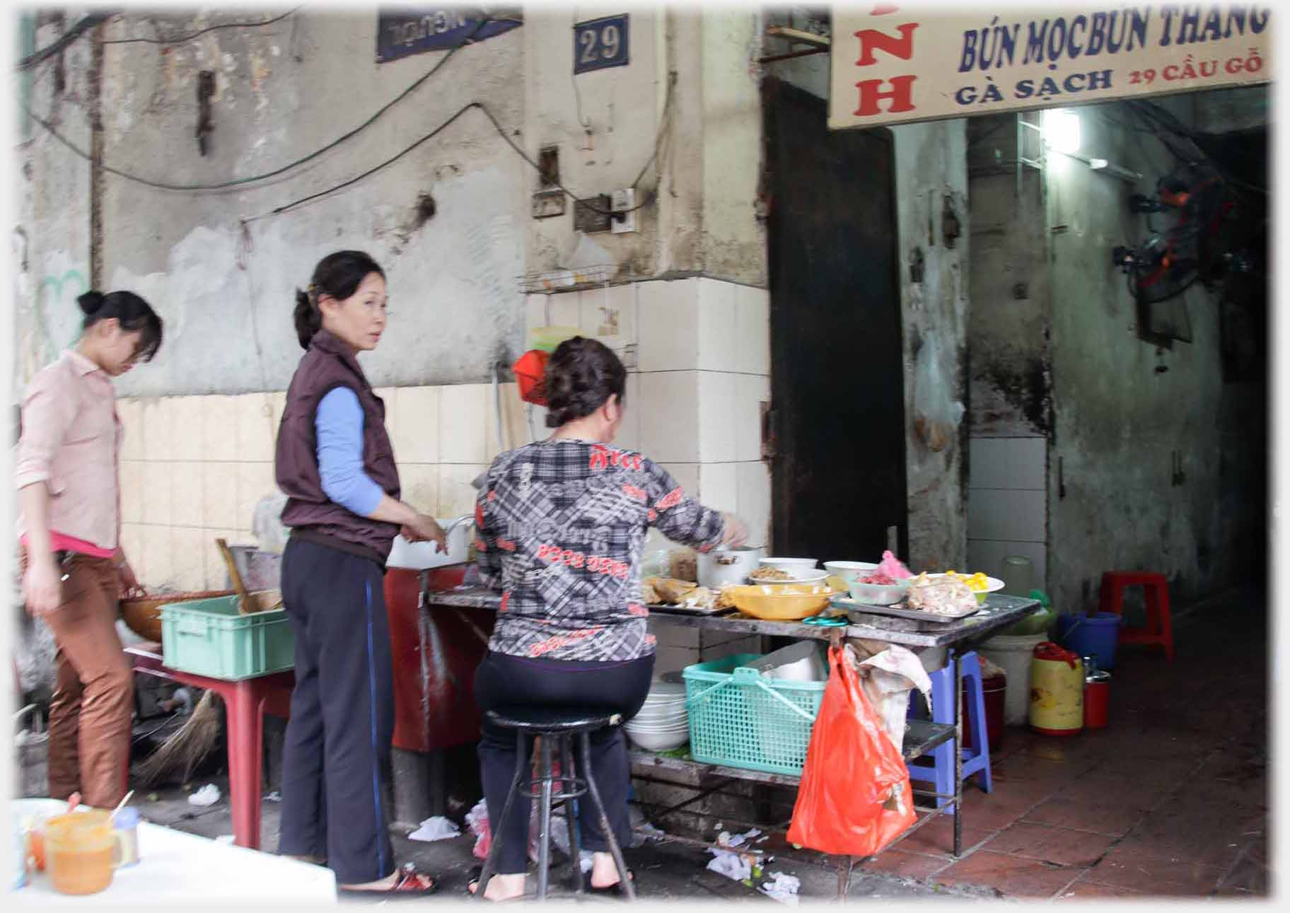 Table with bowls of food being sorted by three women.