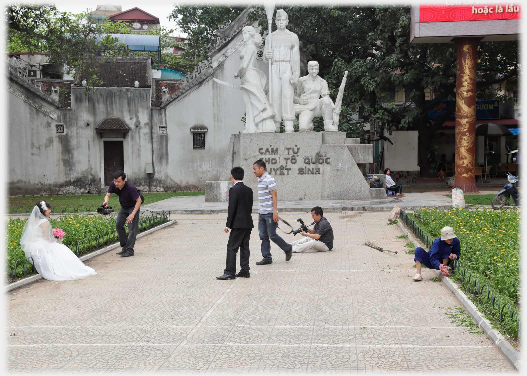 Photographic team taking pictures of bride by war memorial.