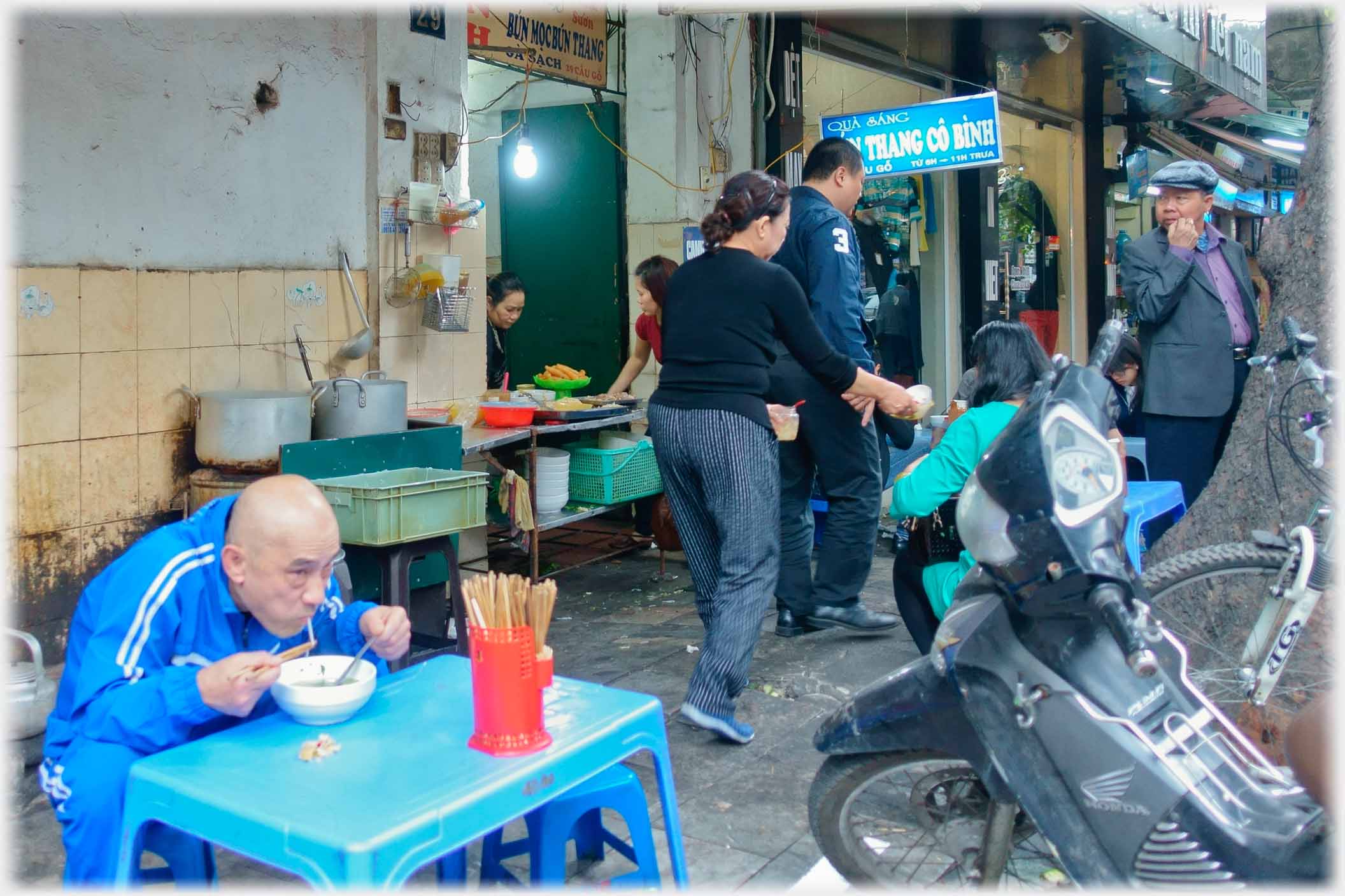 Man eating noodles, face a few inches from his bowl.