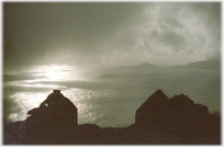 Cloud swirling over sea with house ruins.