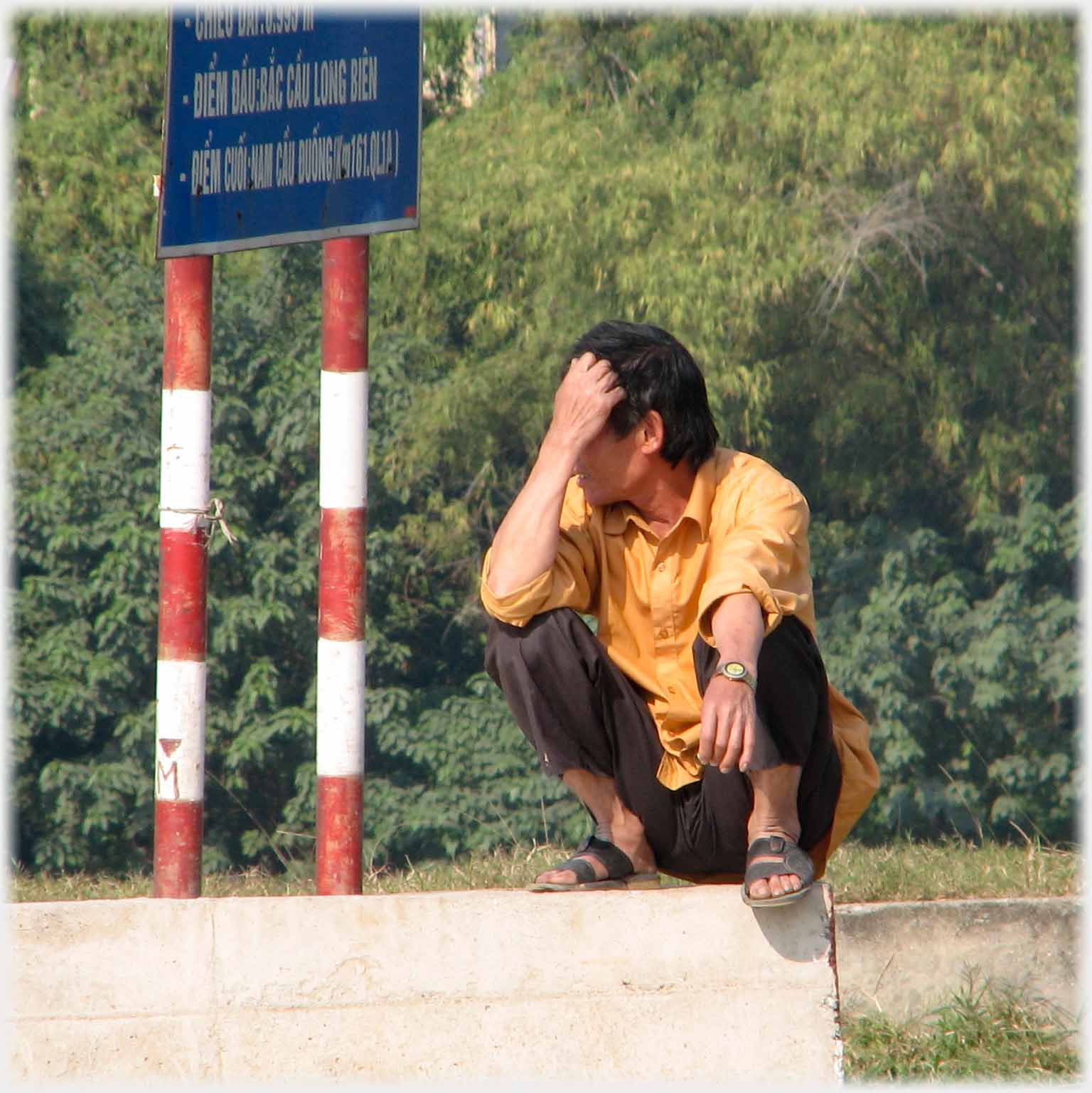 Man squatting on wall.