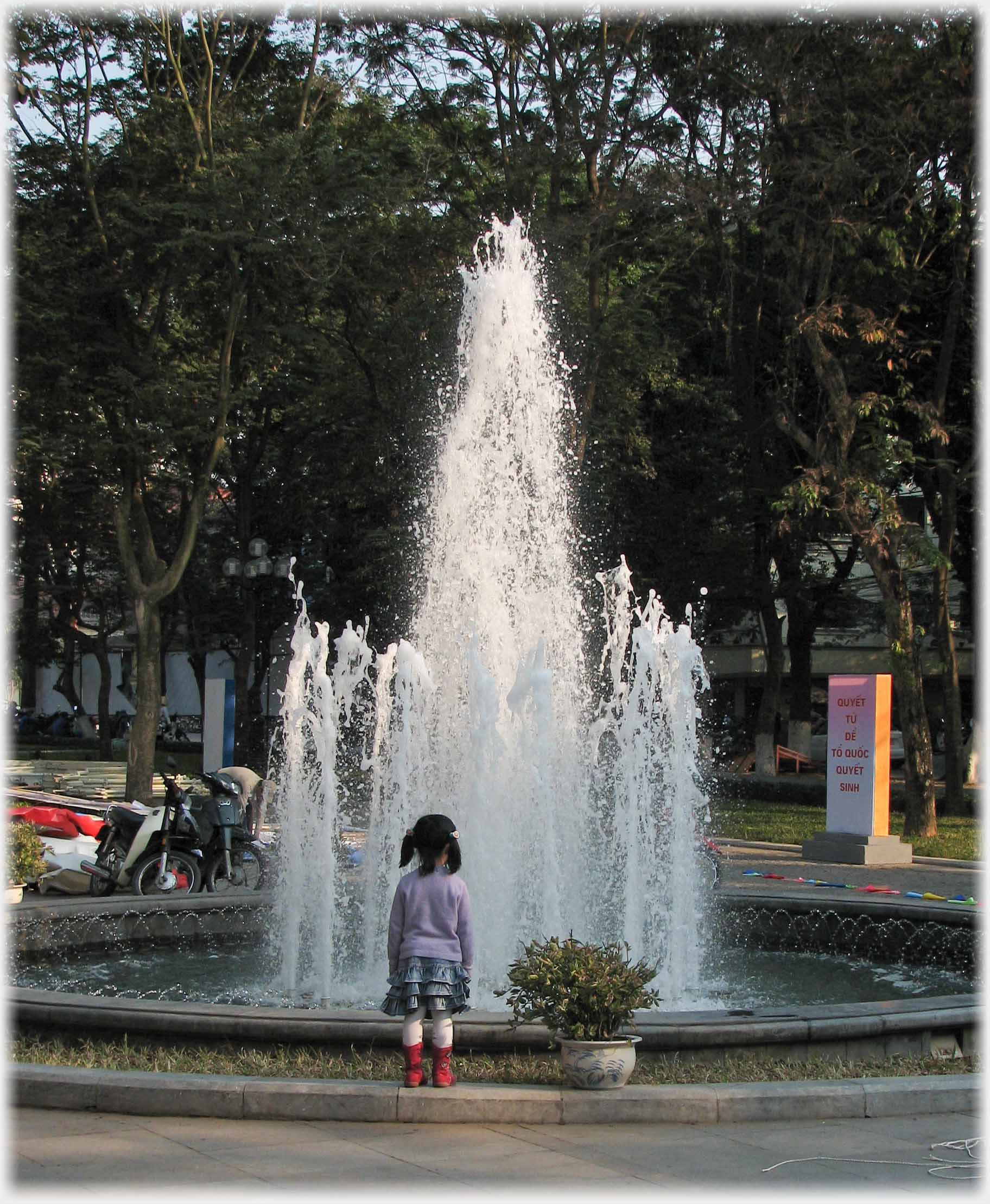 Small girl in front of fountain in evening light.