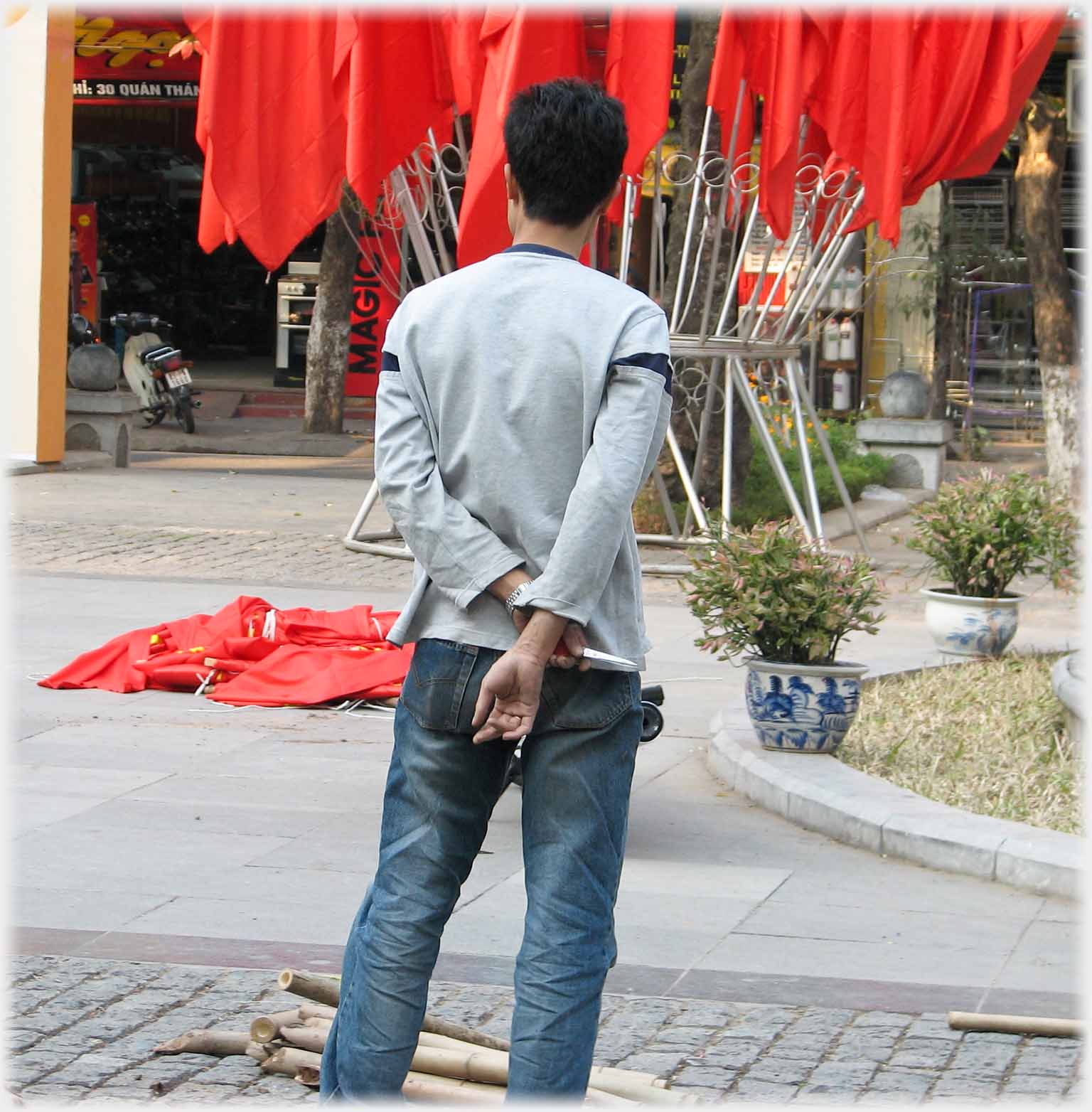 Back of man standing holding scissors looking at flag display