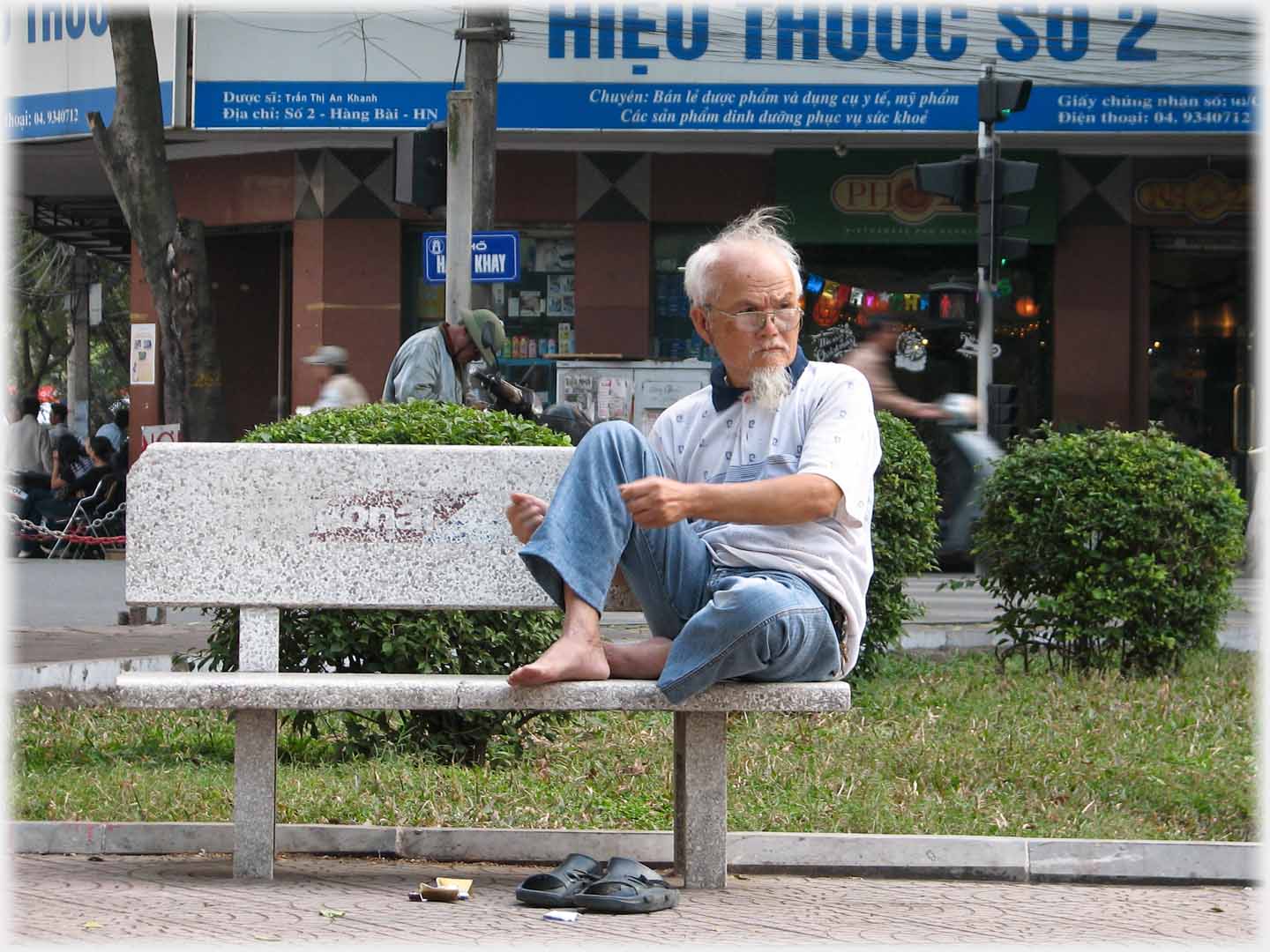 Man, feet up on park seat, holding hands as though holding book.