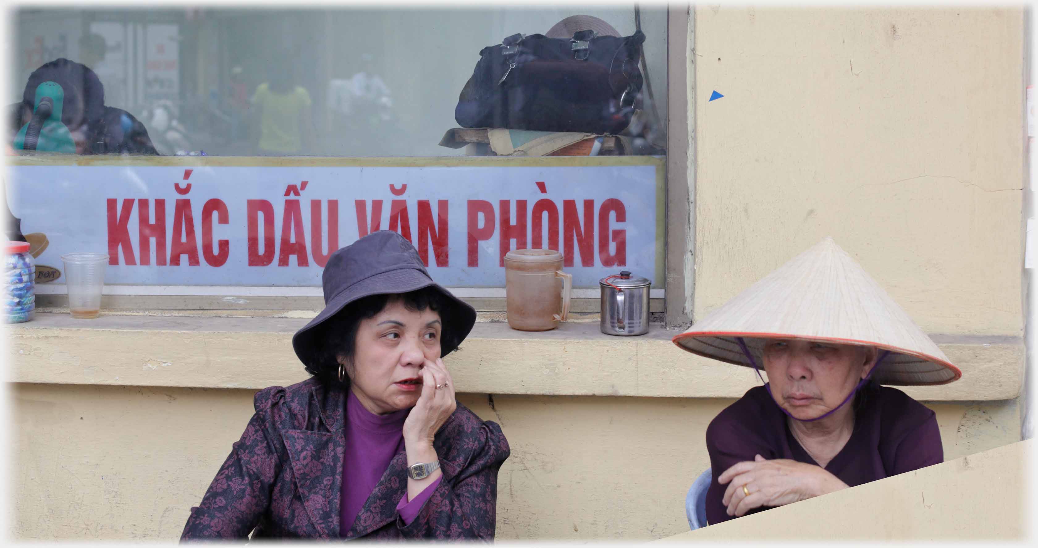 Two women in hats, with conspiritorial air.