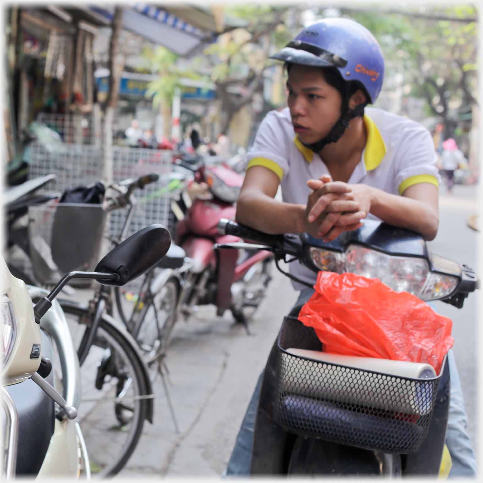 Man in crash helmet sitting on motorbike fingers interlocked.