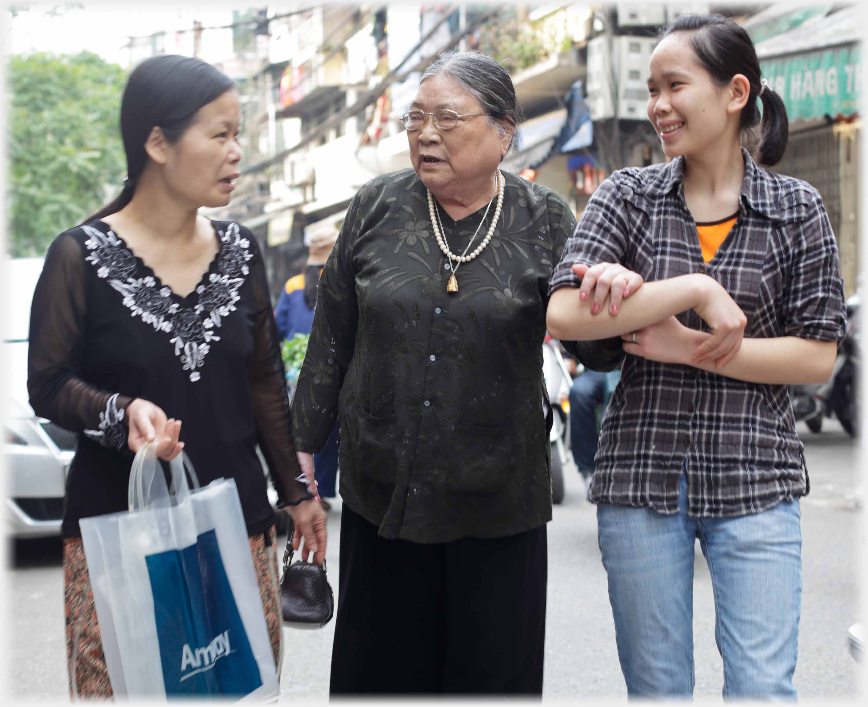 Older woman talking to younger one on one side and holding arms with another on the other side.