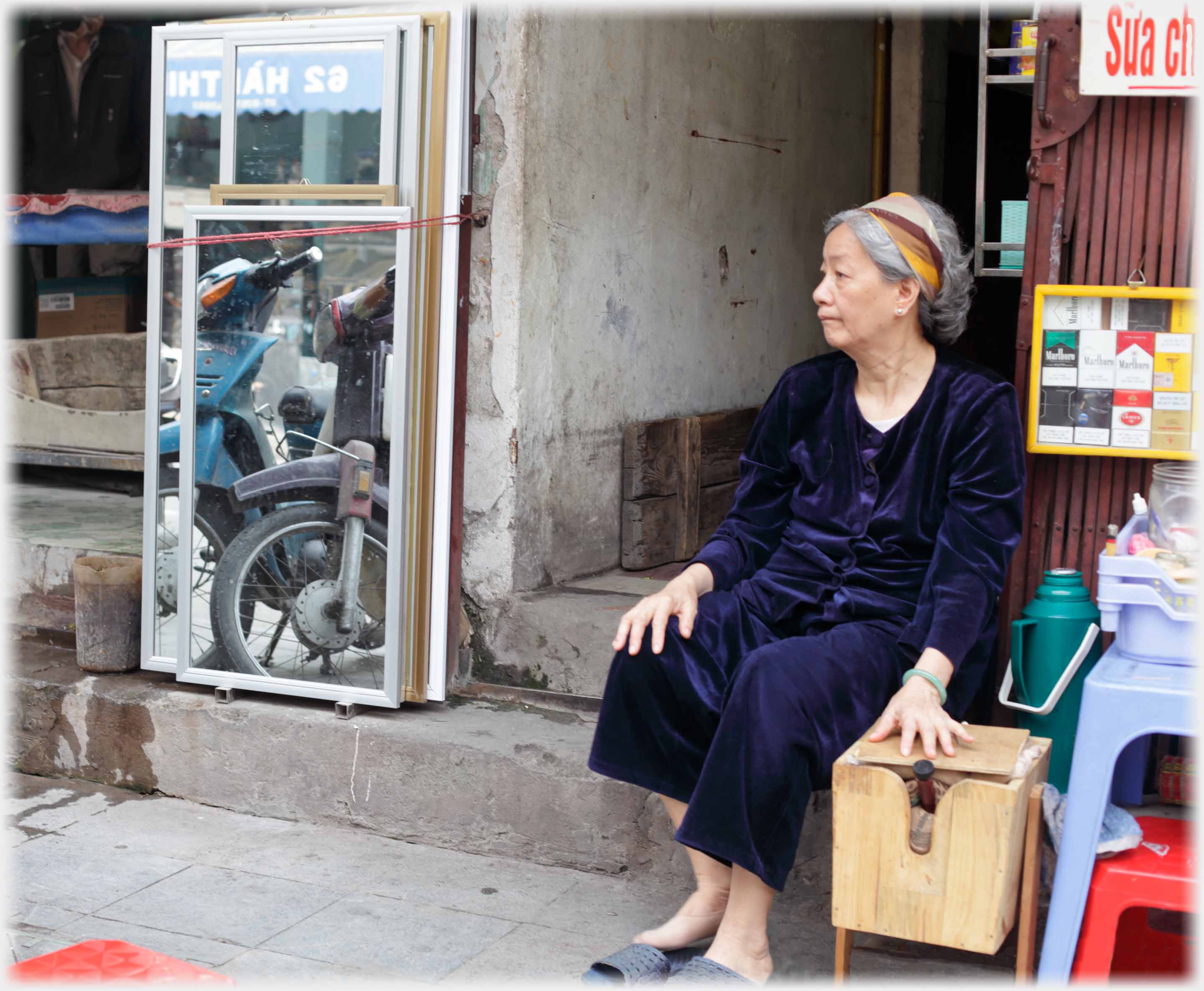 Older woman sitting and looking left with hand on box.