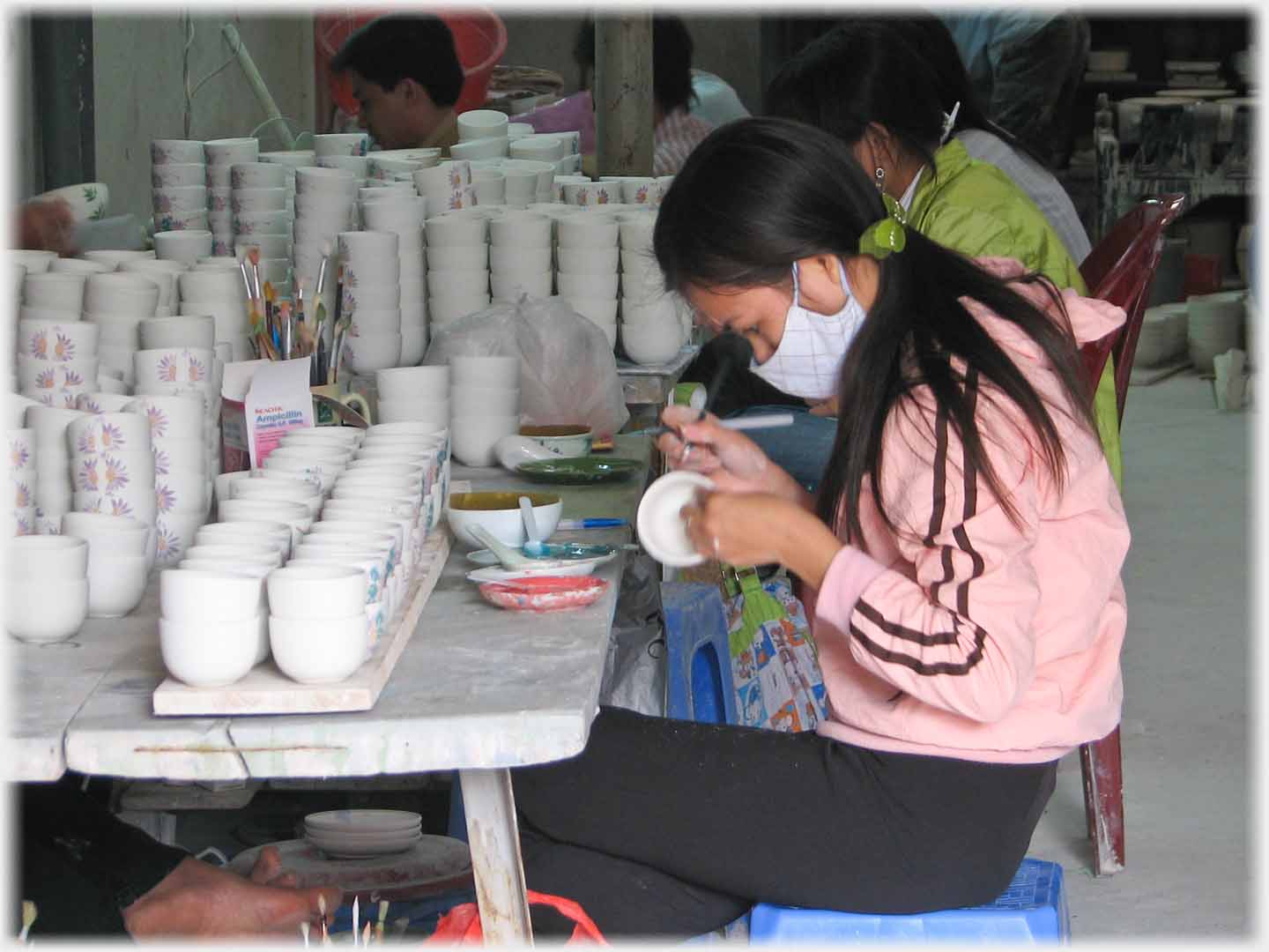 Woman sitting at table with scores of bowls stacked in front of her.