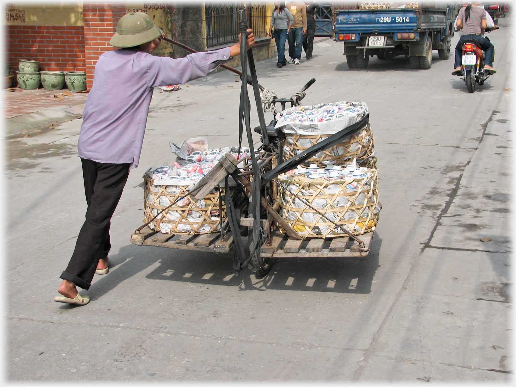 Man wheeling adapted loaded bicycle.