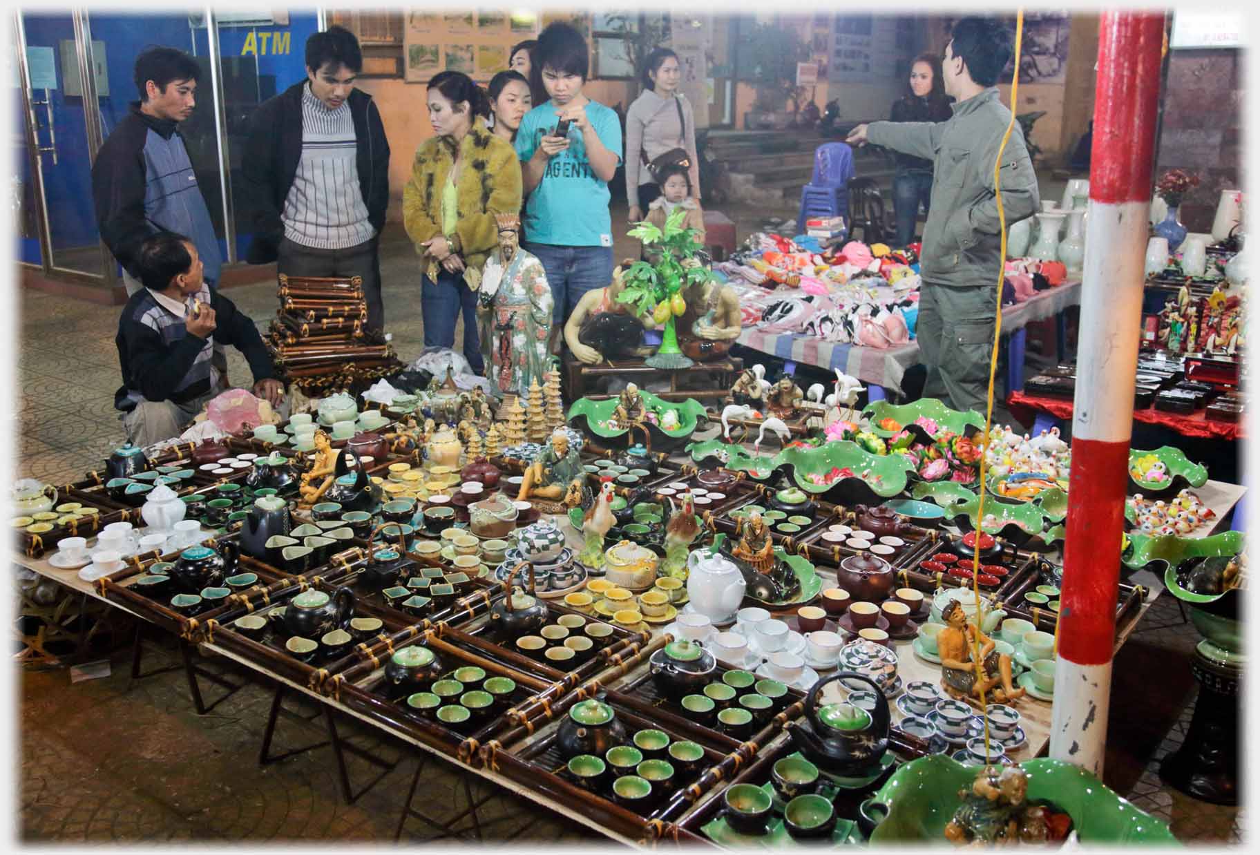 Customers beyond a stall covered with small ceramic items.