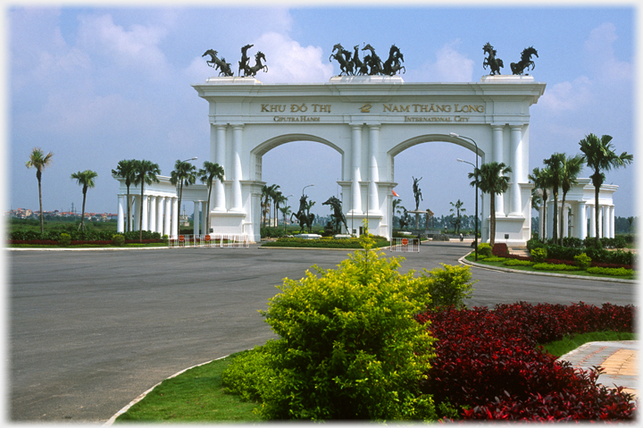 Large double white arch with three groups of black skeletal prancing horses on top.