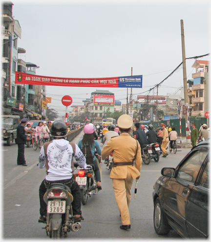 Two policemen walking amongst dense traffic.