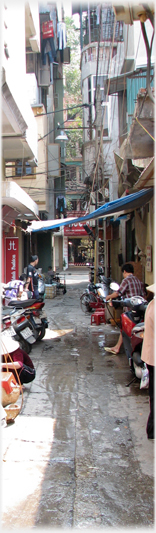 Buildings rising many stories on either side of narrow lane.