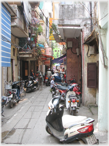 View along lane with cycles and motorbikes parked.