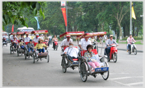 Line of rickshaws progressing along Ha Noi street.