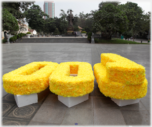 The four numerals of 1000 made out of plastic flowers waiting on the ground to be used.
