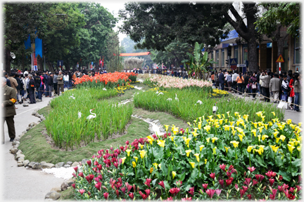 Street covered in flowerbeds with crowds on either side.