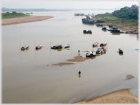 House boats on river with man wading by them.