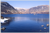 Loch with remains of winter snow on the hills round it.