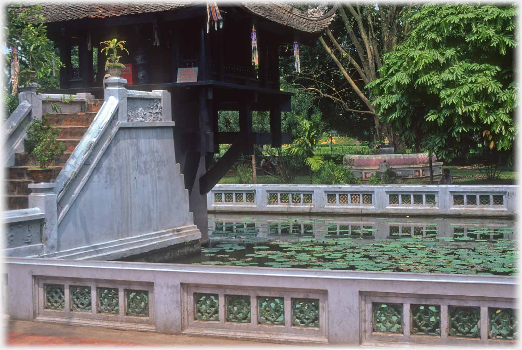 Steps and pagoda with pool and trees beyond.