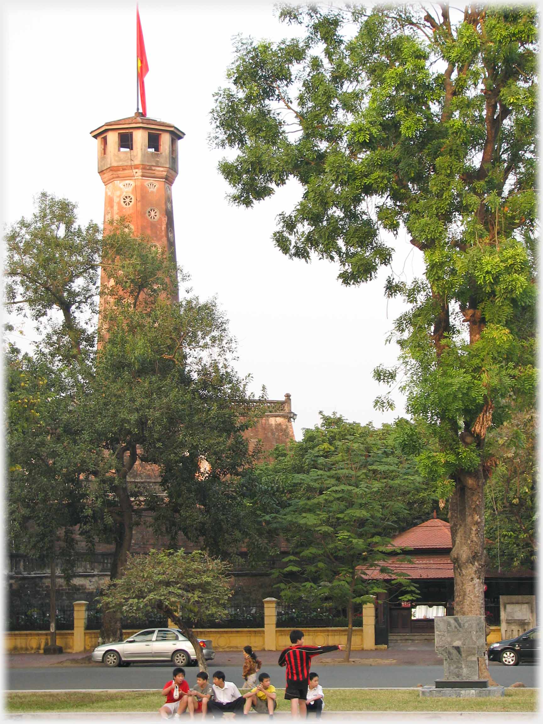 Tower with flag and children on grass below.