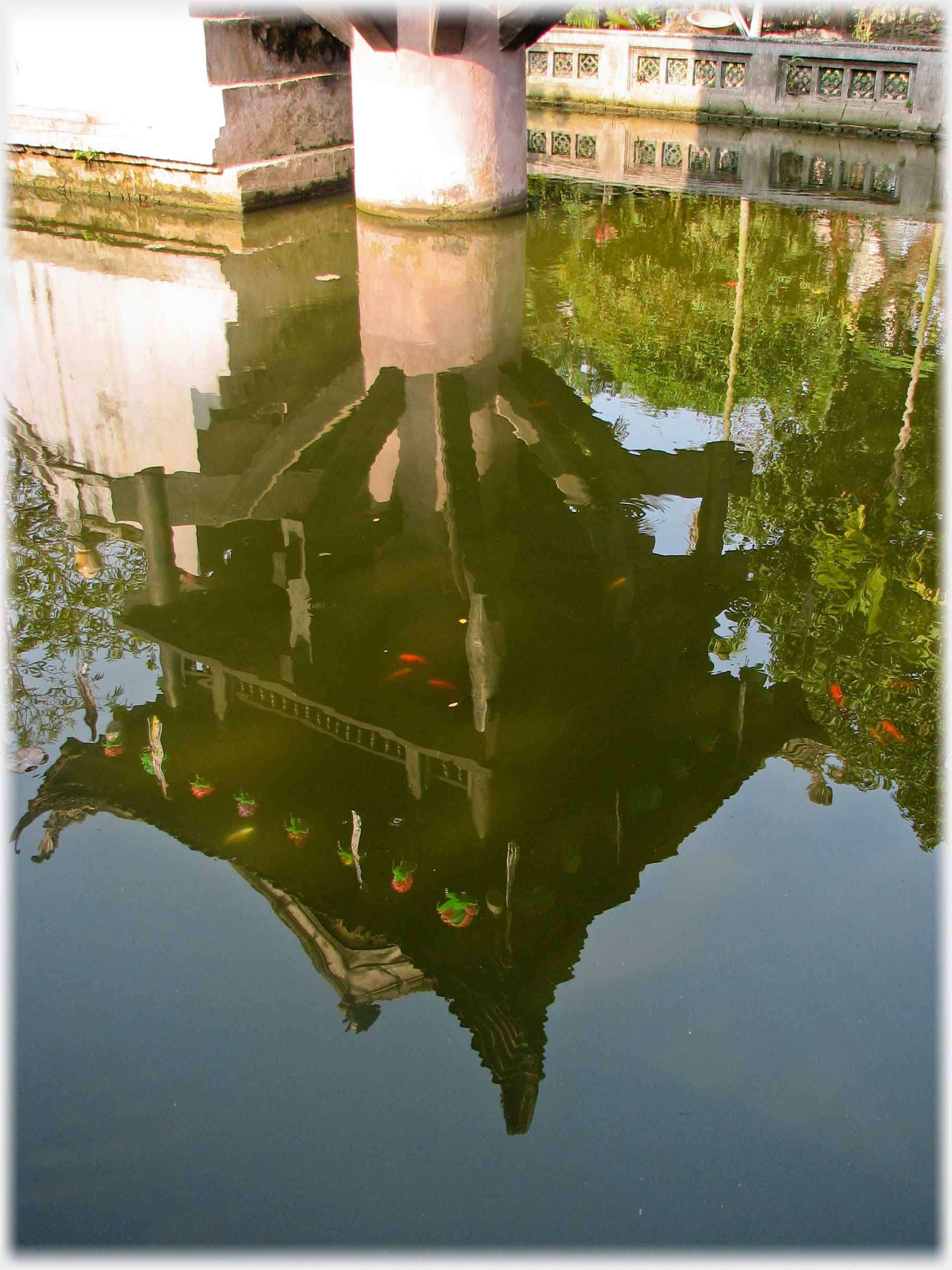 Reflection in pool of pagoda on column.