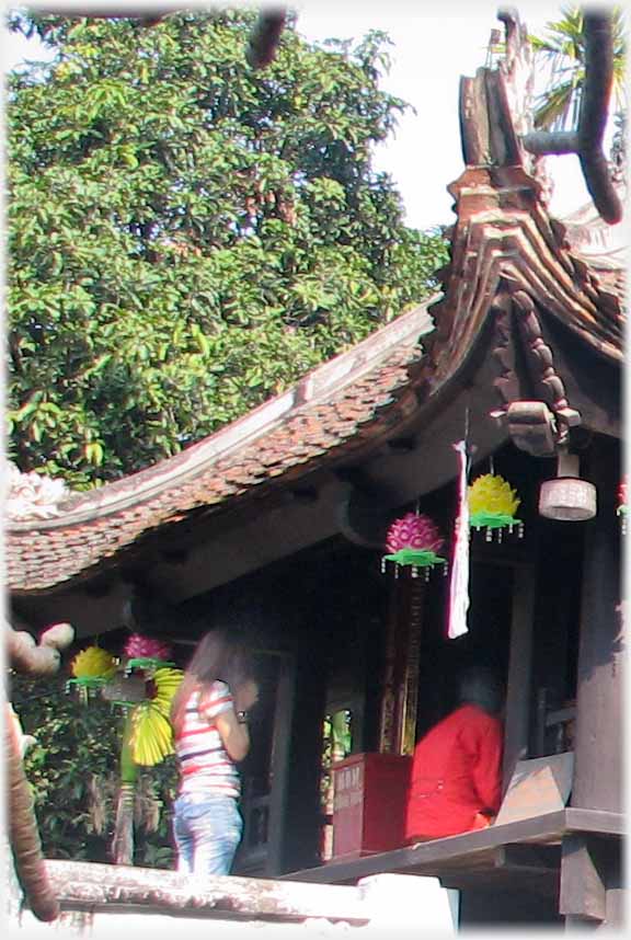 Woman standing at entrance praying, person kneeling on entranceway.