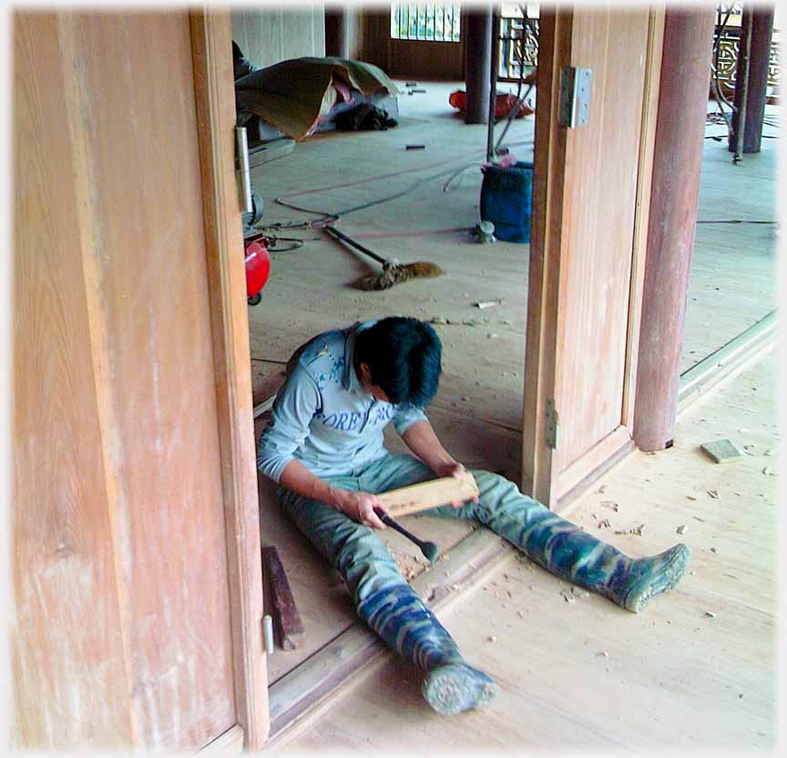 Man sitting across doorway, legs strait out in front.