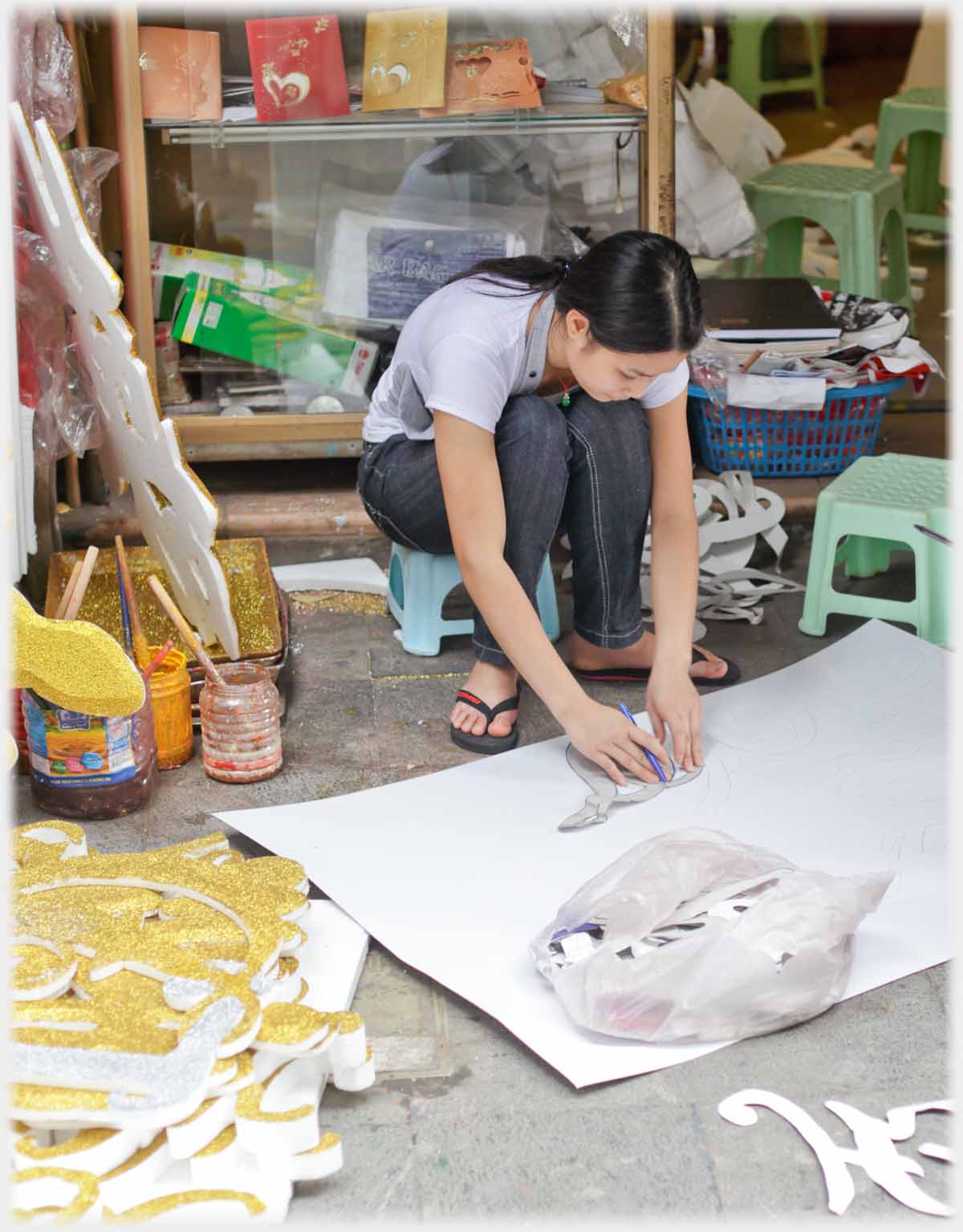 Woman working on paper on pavement.