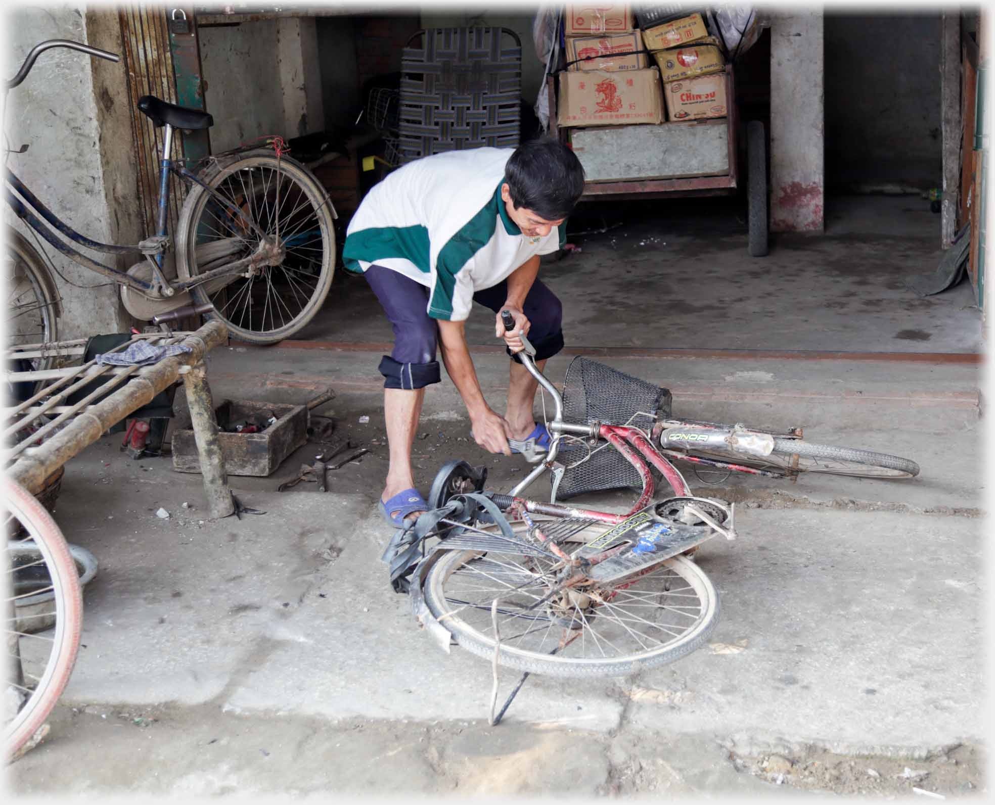 Man bending over cycle with spanner.