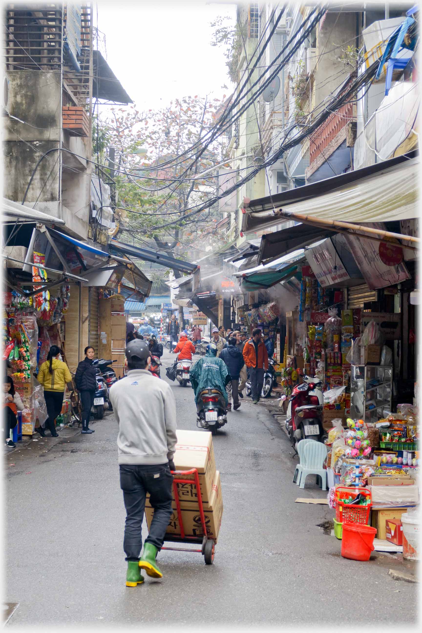 Man pushing barrow in narrow road.