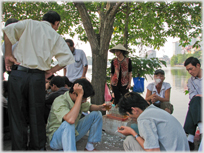 Group hunched around chess game, tea in baclground.